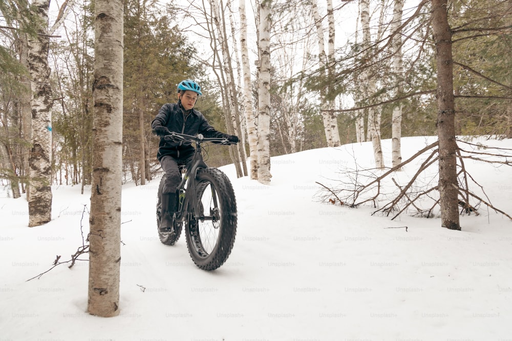 a man riding a bike through a snow covered forest