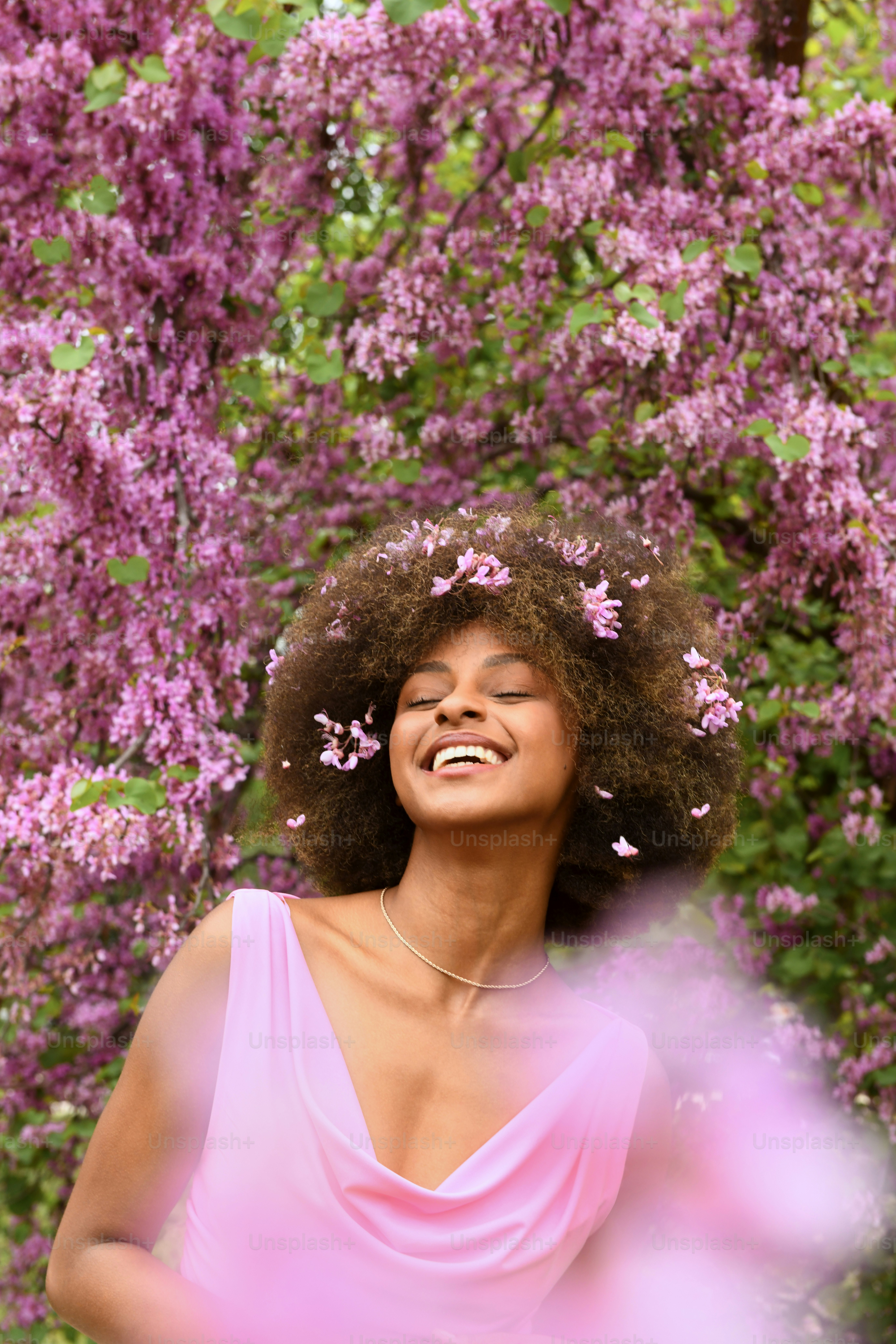 a woman in a pink dress standing in front of purple flowers