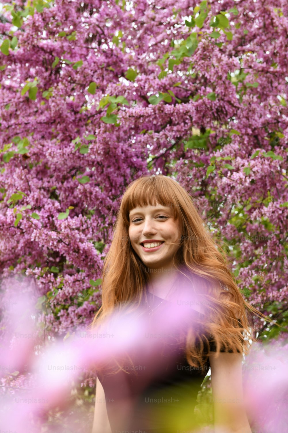a woman standing in front of a tree with purple flowers