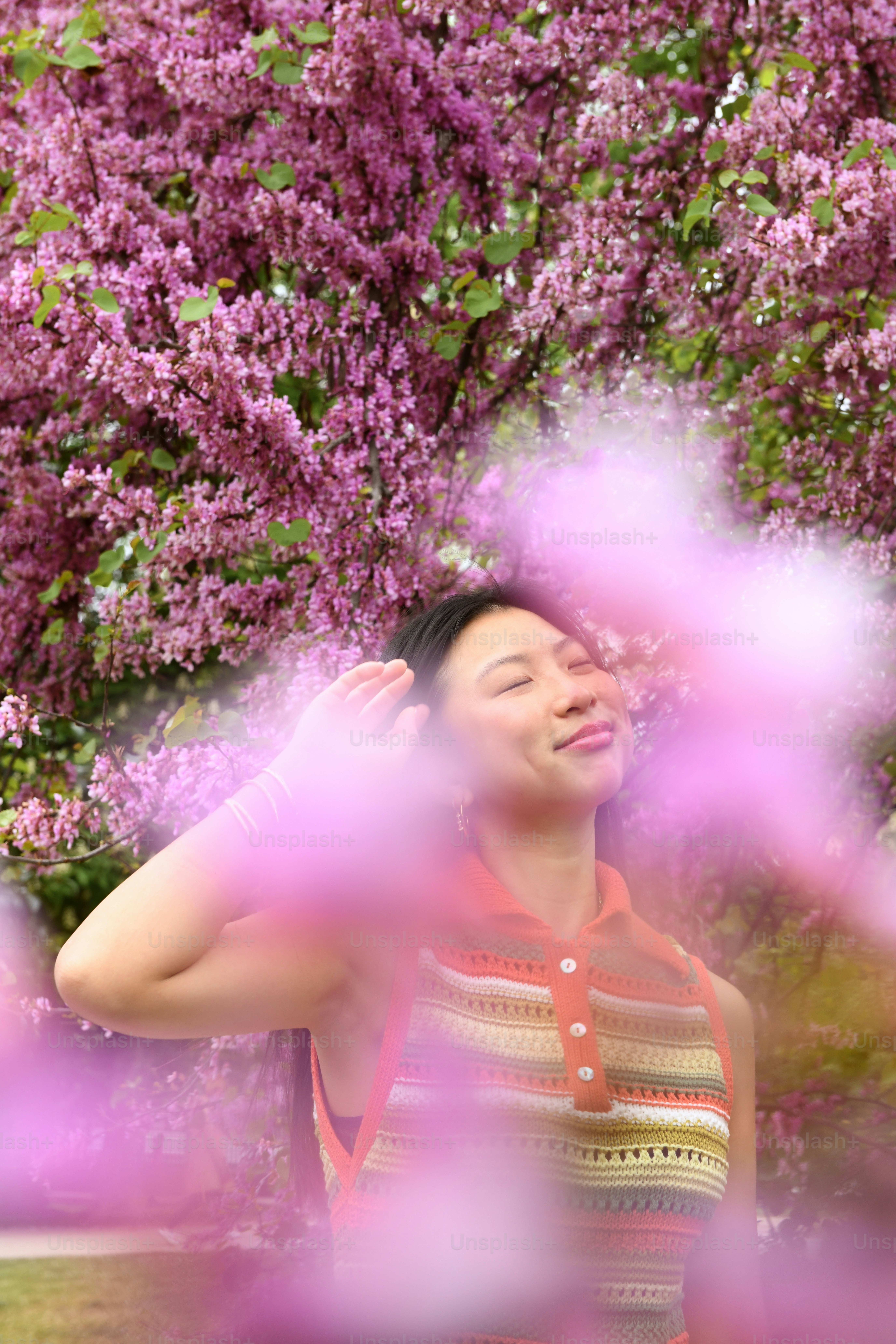 a woman standing in front of a tree with purple flowers