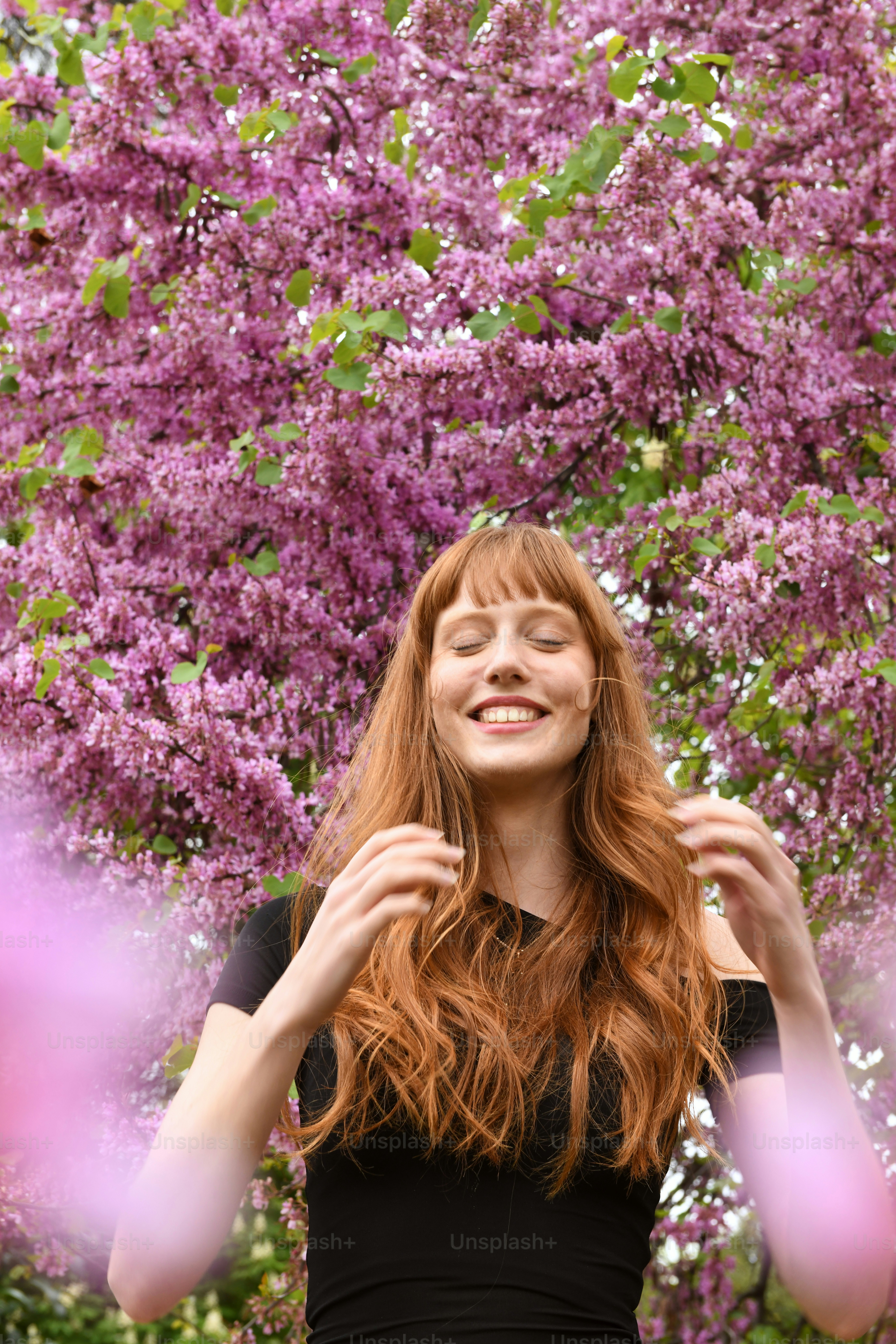 a woman standing in front of a tree with purple flowers