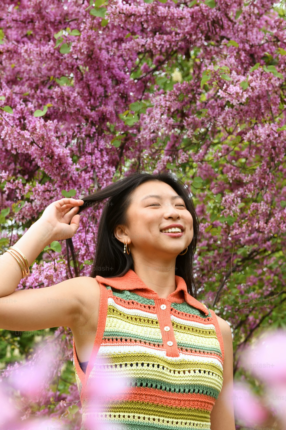 紫色の花を持つ木の前に立つ女性