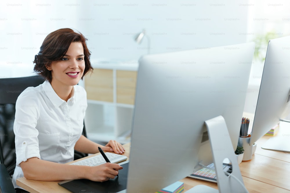 オフィスのコンピューターでプロジェクトに取り組む女性。デジタル描画タブレットに取り組む女性デザイナー。高解像度
