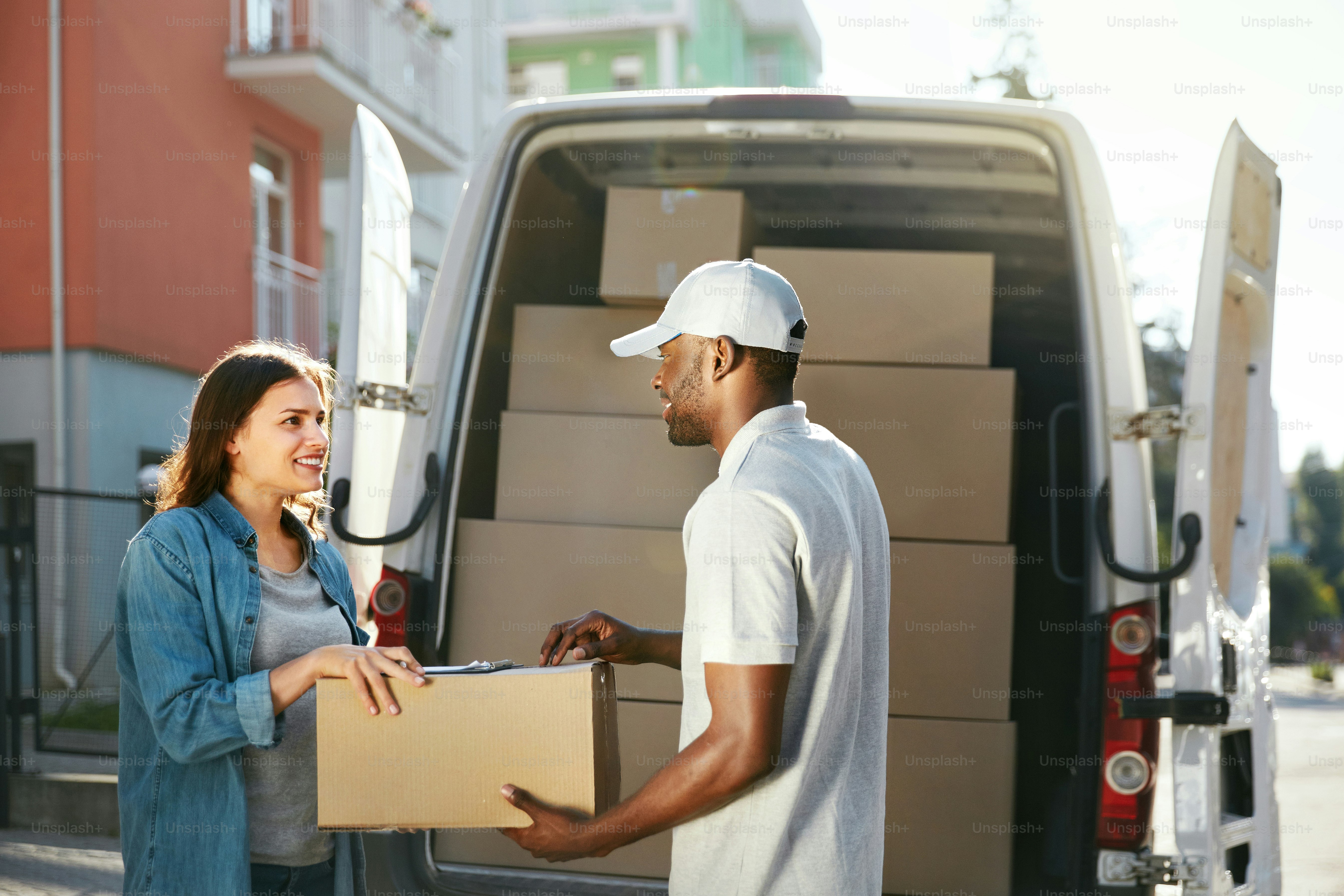 Delivery Service. Courier Delivering Package To Woman Near Truck Car With Boxes Outdoors. High Resolution