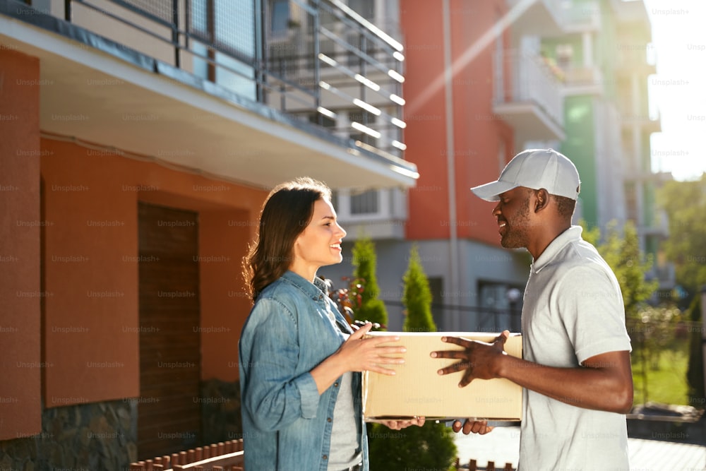 Express Delivery. Courier Delivering Package, Woman Receiving Parcel From Delivery Man Near Home. High Resolution