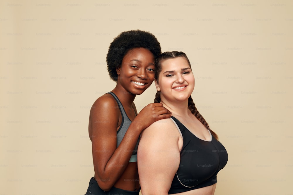 Plus Size Models. Full-figured Women Portrait. Brunette And Blonde In Black  Bodysuits Posing On Beige Background. Smiling Female Looking At Camera.  Body Positive As Lifestyle. Stock Photo, Picture and Royalty Free Image.