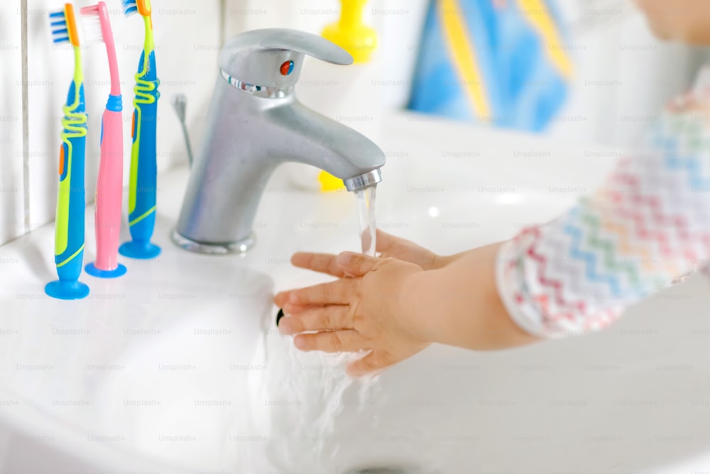 Closeup of little toddler girl washing hands with soap and water in bathroom. Close up child learning cleaning body parts. Morning hygiene routine. healthy kid at home or nursery.