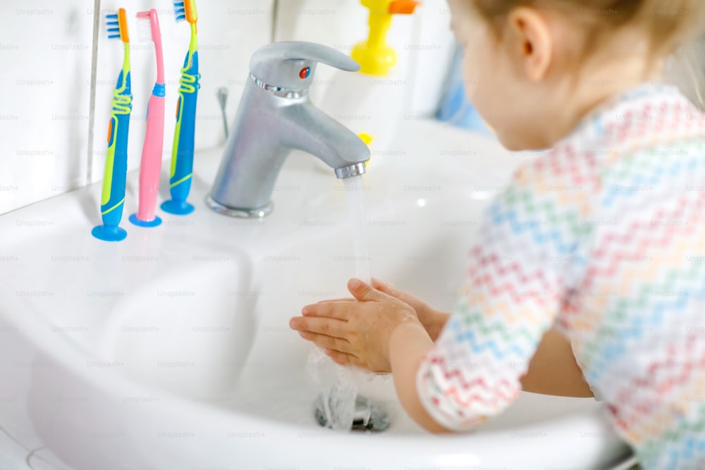 욕실에서 비누와 물로 손을 씻는 어린 소녀의 클로즈업. 신체 부위를 청소하는 아이를 닫습니다. 아침 위생 루틴. 집이나 보육원에서 건강한 아이.