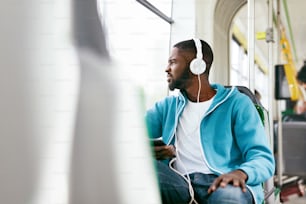 Man Riding Bus, Listening Music With Headphones And Phone In Public Transport. Handsome African Male With Earphones. High Resolution