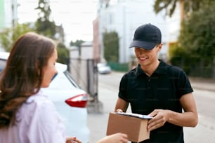 Express Delivery Service. Courier Man Delivering Package To Woman Outdoors. High Resolution