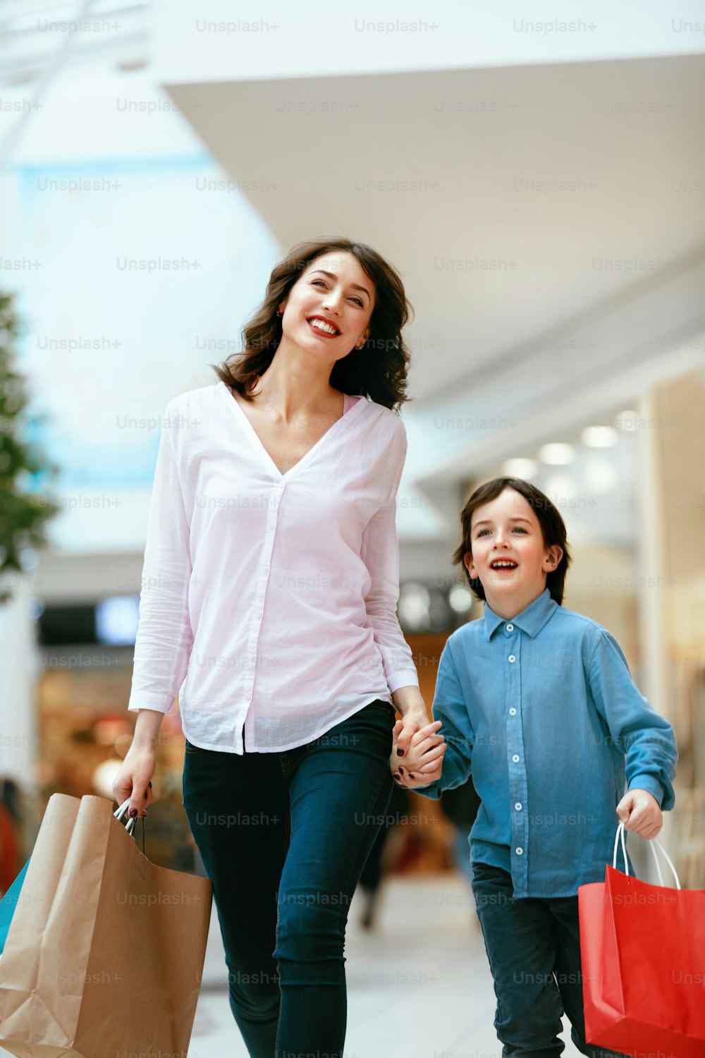 Compras. Jovem mãe e criança segurando sacolas; Passando tempo juntos no shopping. Alta Resolução.