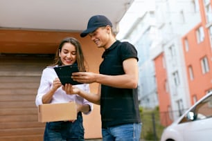 Delivery Courier. Man Delivering Package To Woman. Client Signing Delivery Documents. High Resolution