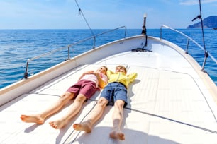 Dois meninos pequenos, melhores amigos desfrutando de passeio de barco à vela. Férias em família no oceano ou no mar em dias ensolarados. Crianças sorrindo. Irmãos, escolares, irmãos se divertindo no iate