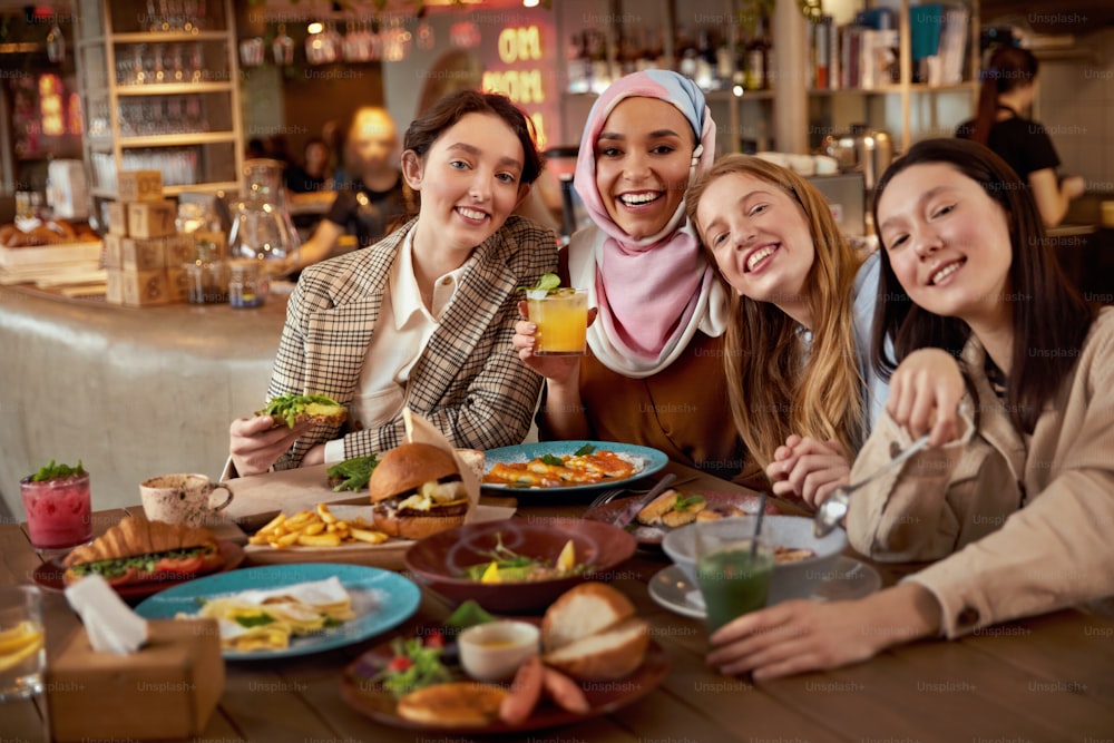 Pranzo. Gruppo di donne nel ritratto del caffè. Ragazze multiculturali sorridenti con cocktail. Amici che si incontrano nel ristorante come parte dello stile di vita.