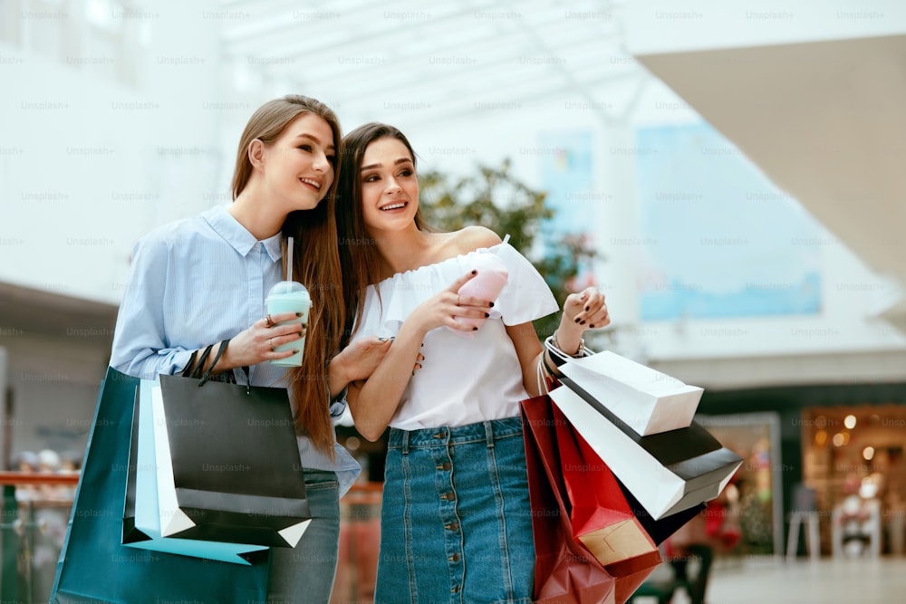 Girls Shopping. Beautiful Happy Female Friends With Colorful Bags In Mall. High Resolution.