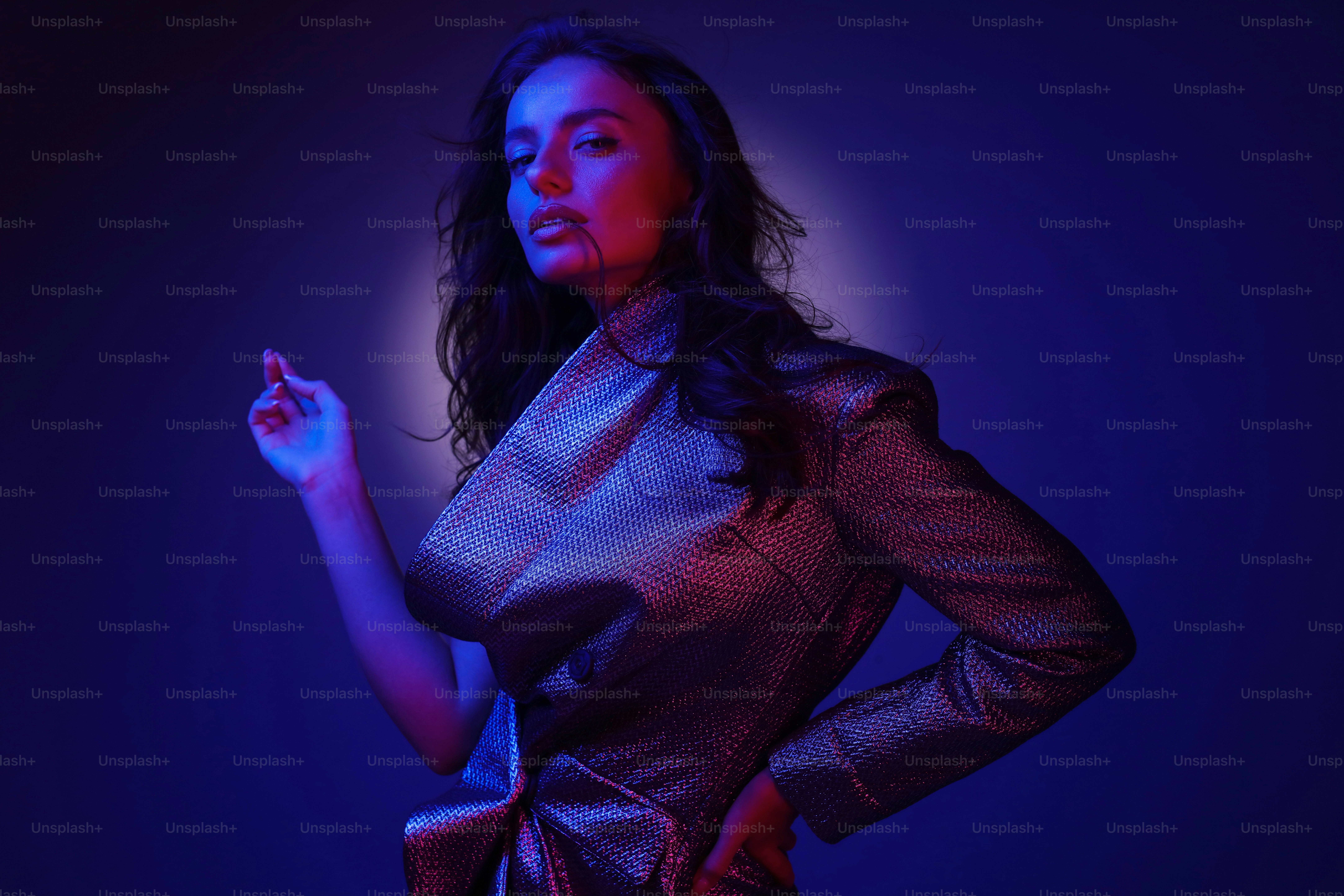 High fashion girl model in stylish clothing in colorful neon lights. Studio portrait of beautiful sexy woman in glamour dress over pink and purple ultraviolet background at night club