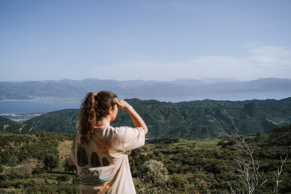 uma mulher em pé no topo de uma colina verde exuberante
