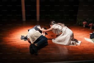 a man kneeling down next to a woman on a wooden floor