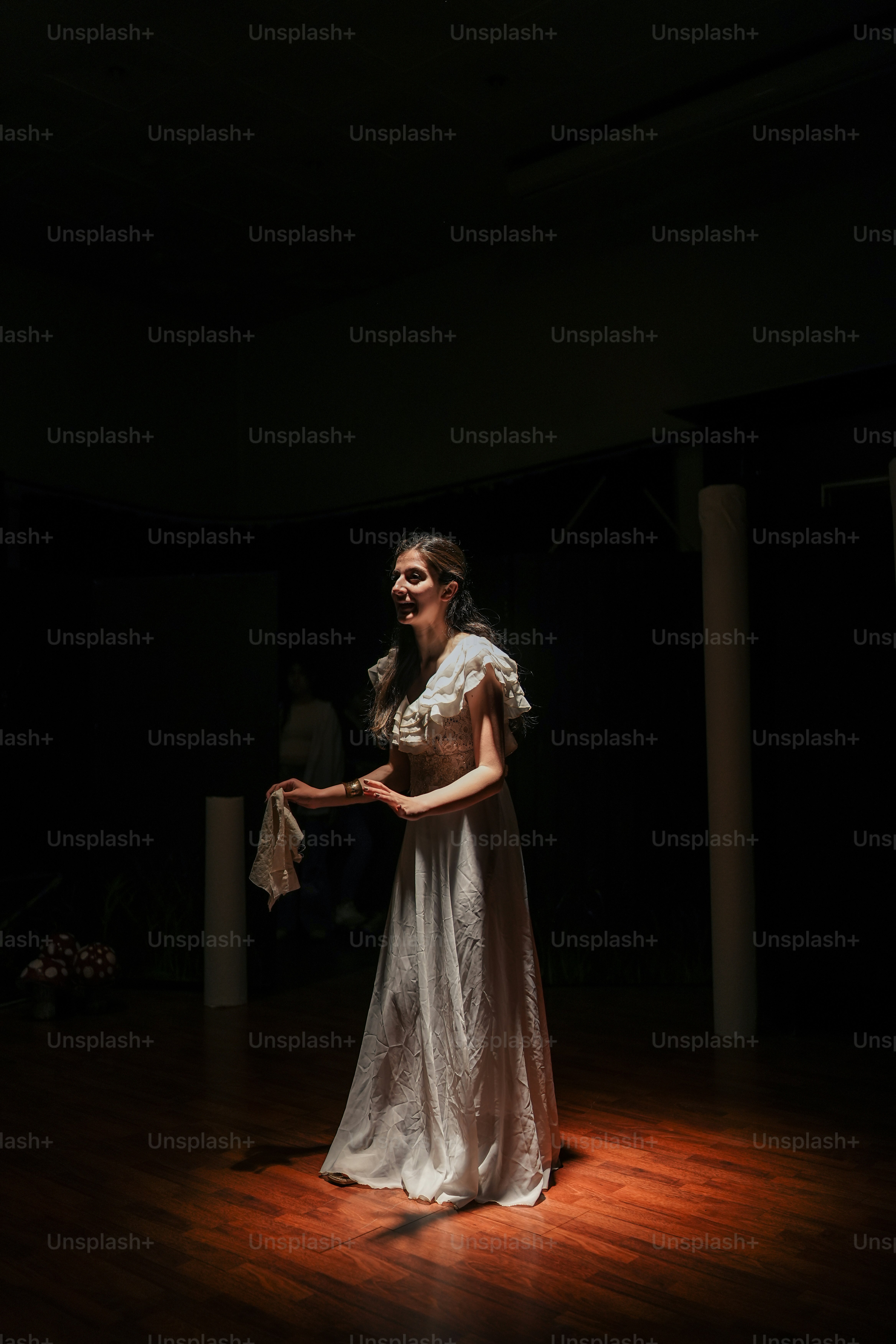 a woman in a white dress standing on a wooden floor