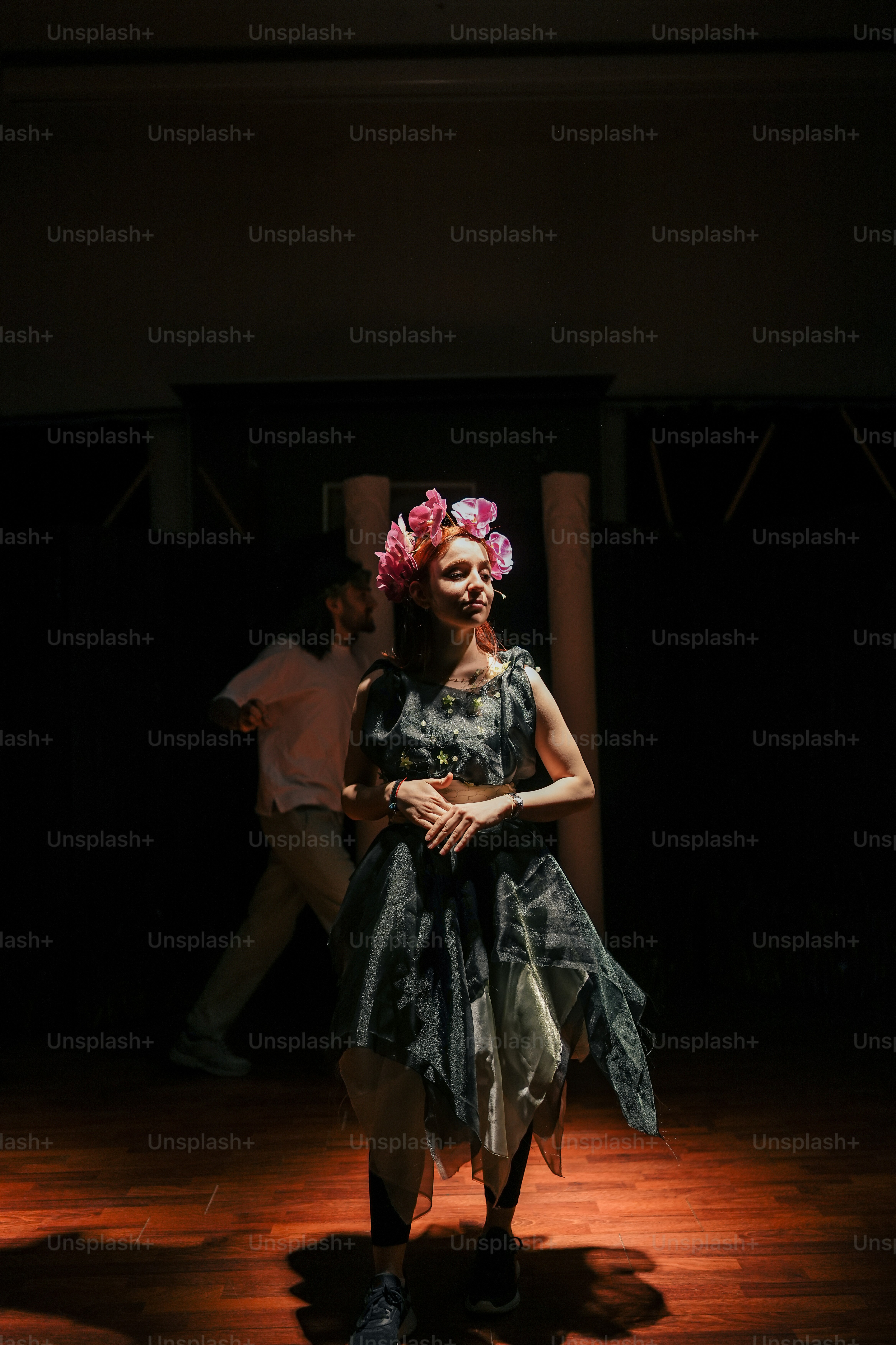 a woman standing on a wooden floor in a dark room
