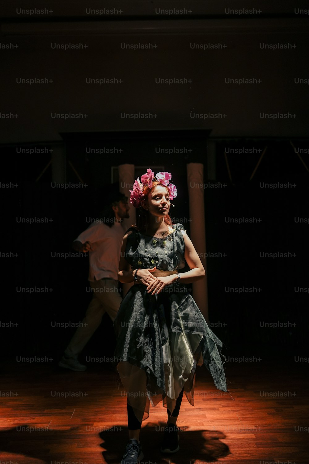 a woman standing on a wooden floor in a dark room