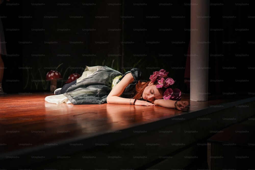 a woman laying on the floor with a flower in her hair