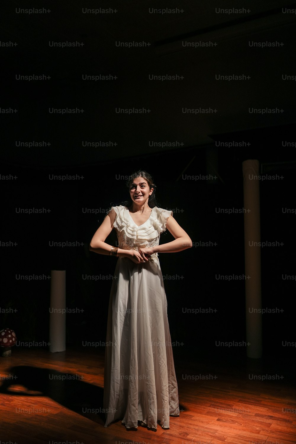 a woman in a white dress standing on a wooden floor