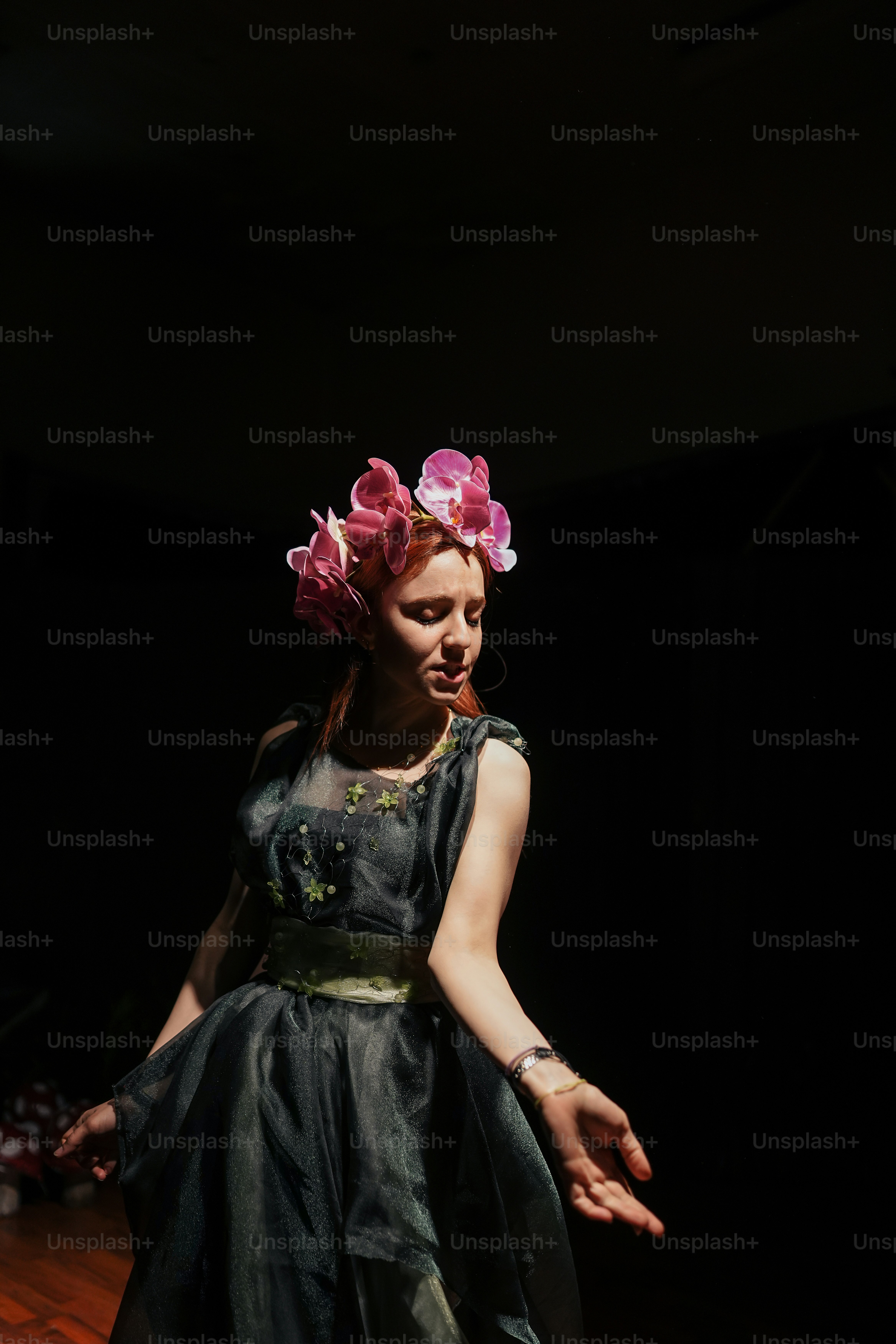 Eine Frau in einem schwarzen Kleid mit rosa Blumen auf dem Kopf