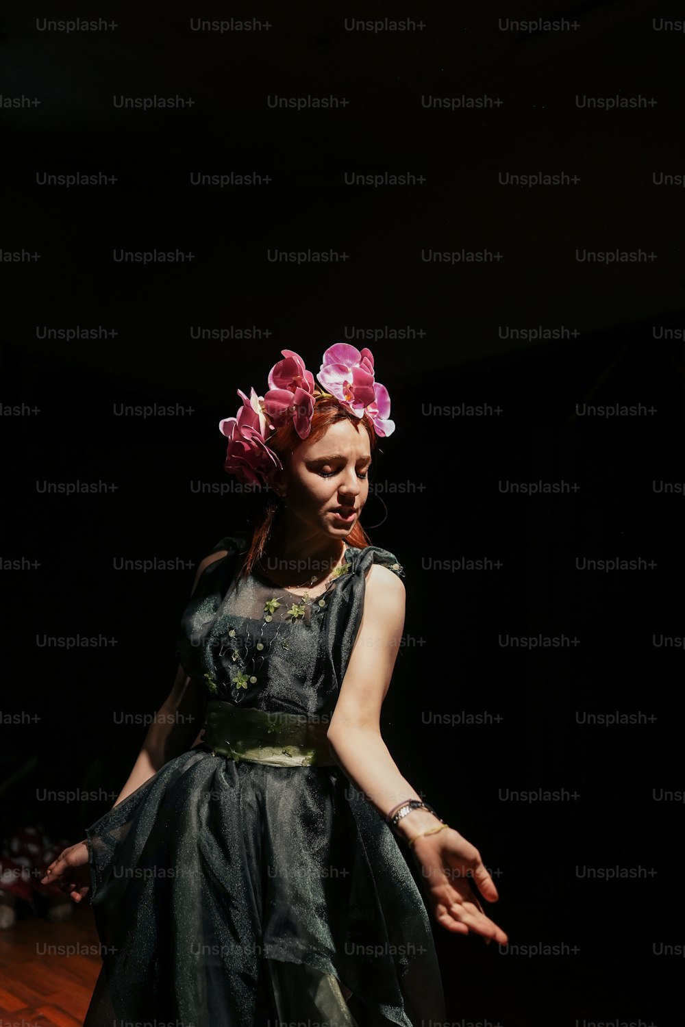 Une femme en robe noire avec des fleurs roses sur la tête