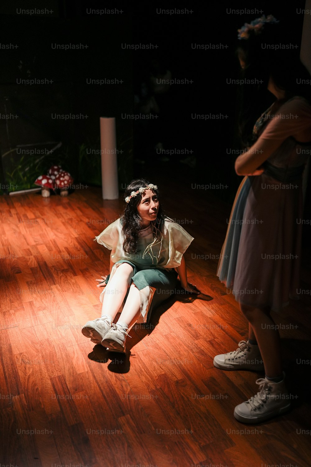uma mulher sentada no chão em um quarto escuro
