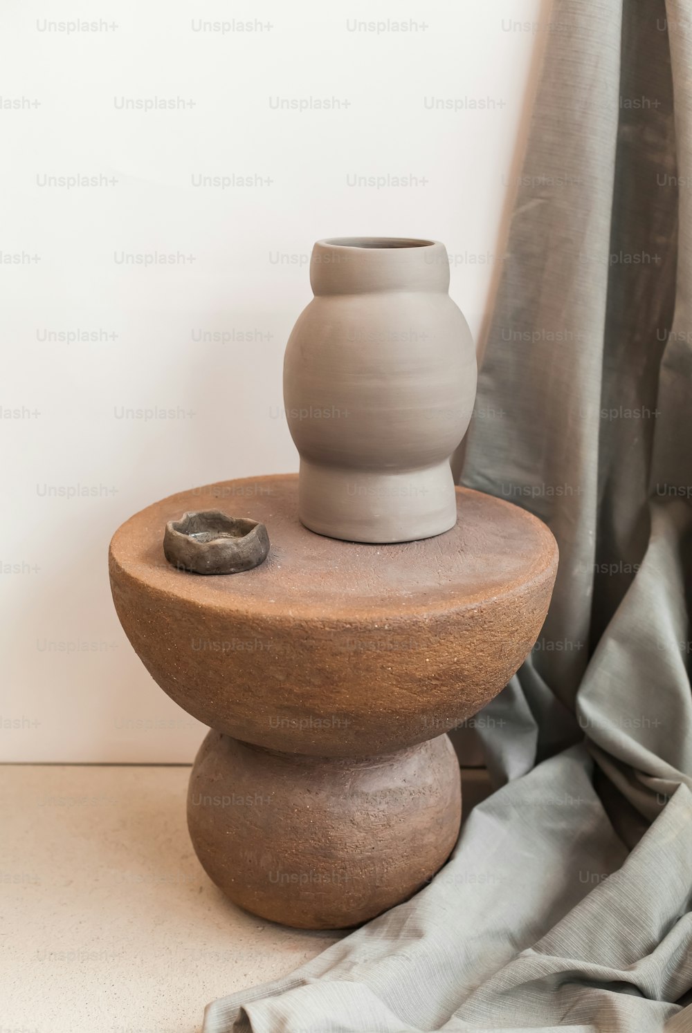 a white vase sitting on top of a wooden stand