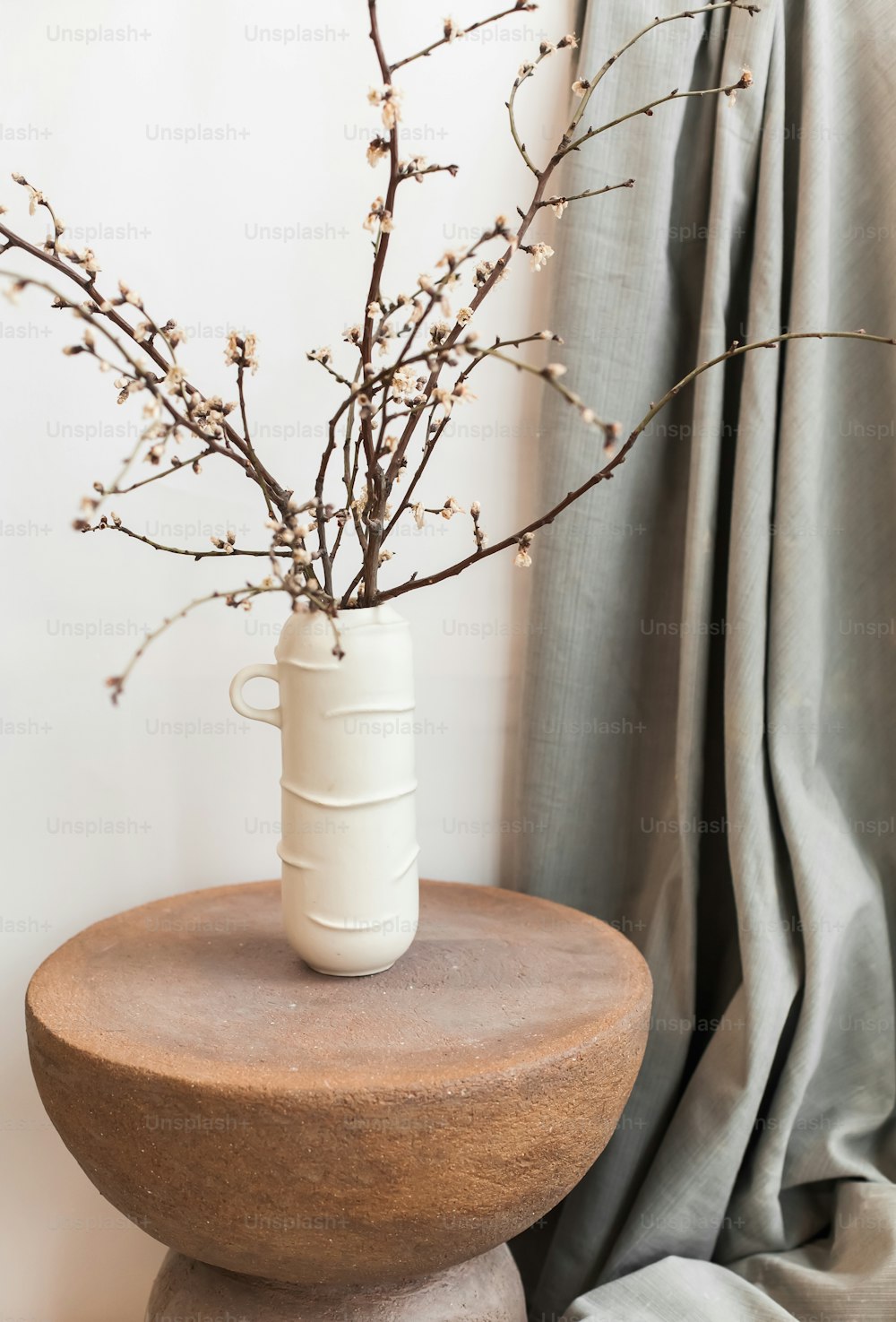 a vase with a branch in it sitting on a table