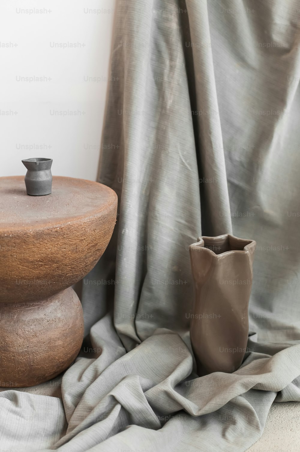 a vase sitting on top of a wooden table next to a curtain