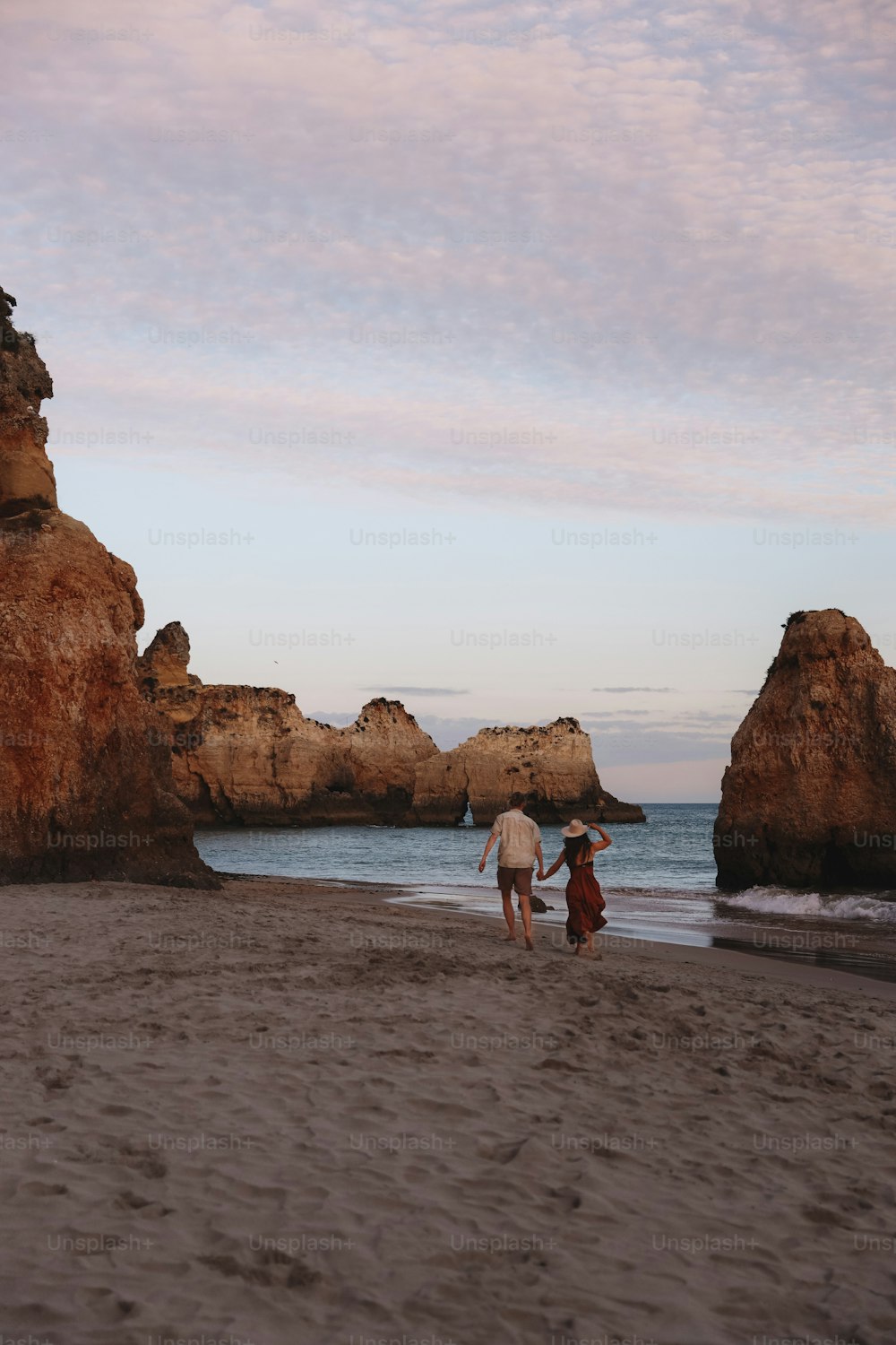 a couple of people standing on top of a sandy beach