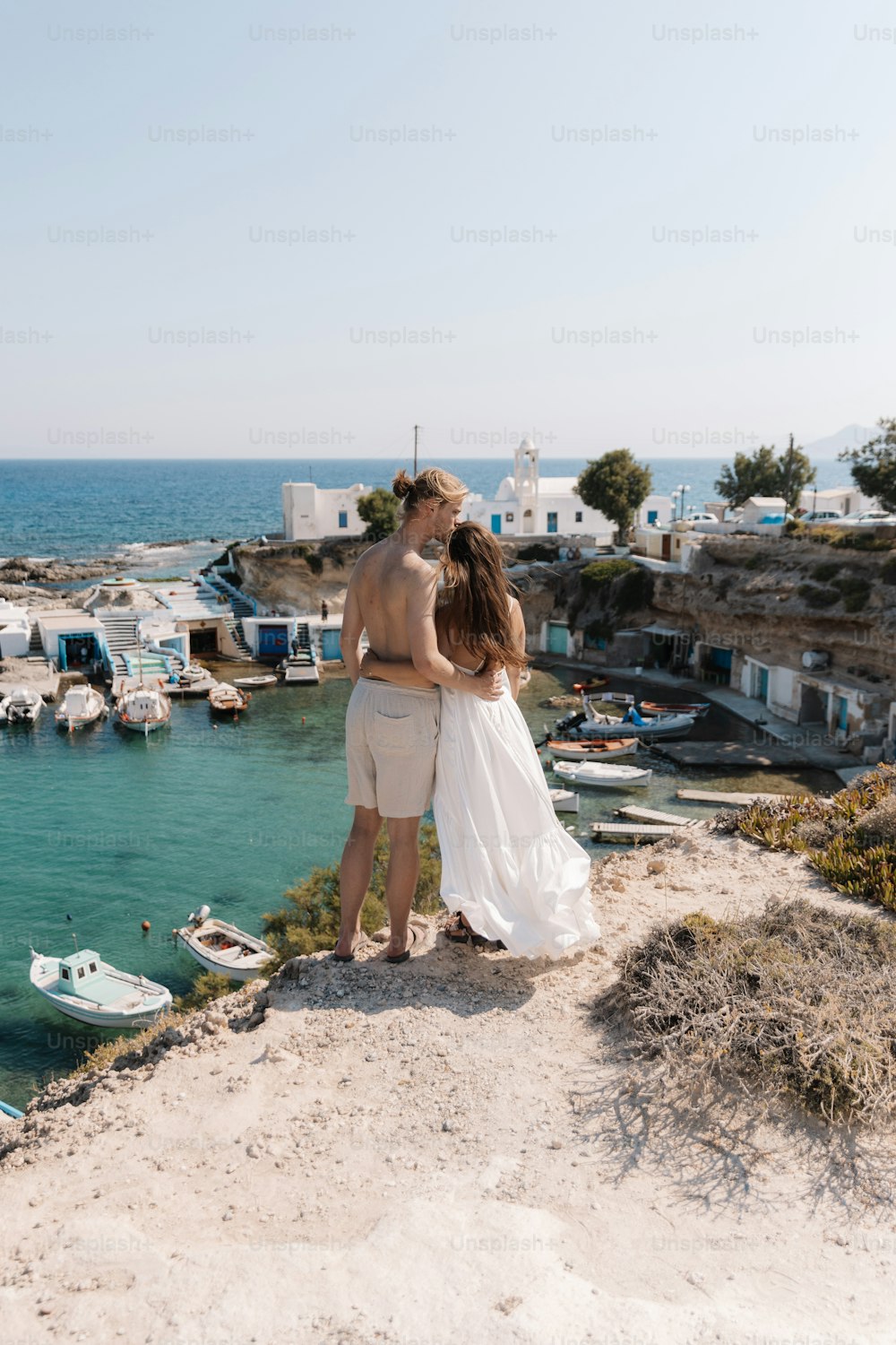 a man and a woman standing on a cliff overlooking the water