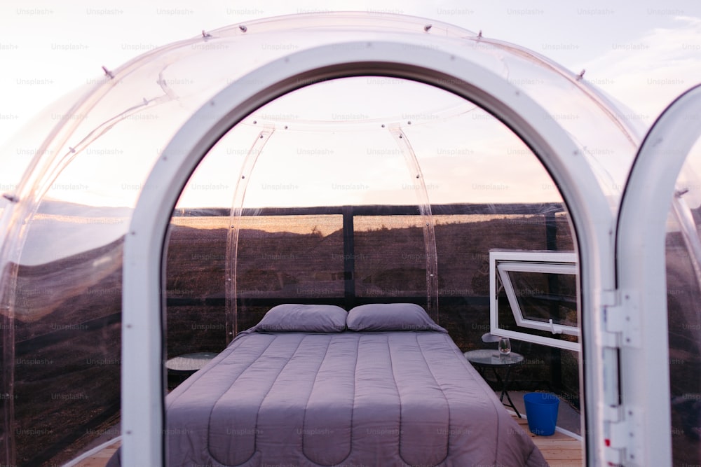 a bed sitting inside of a tent next to a window