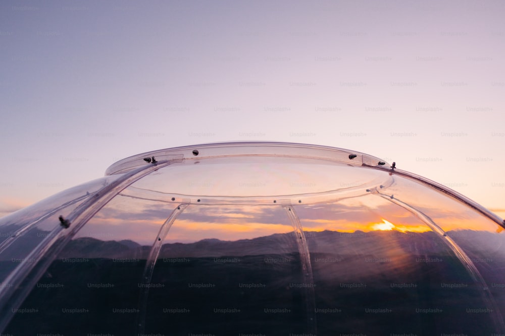 the sun is setting behind a clear dome