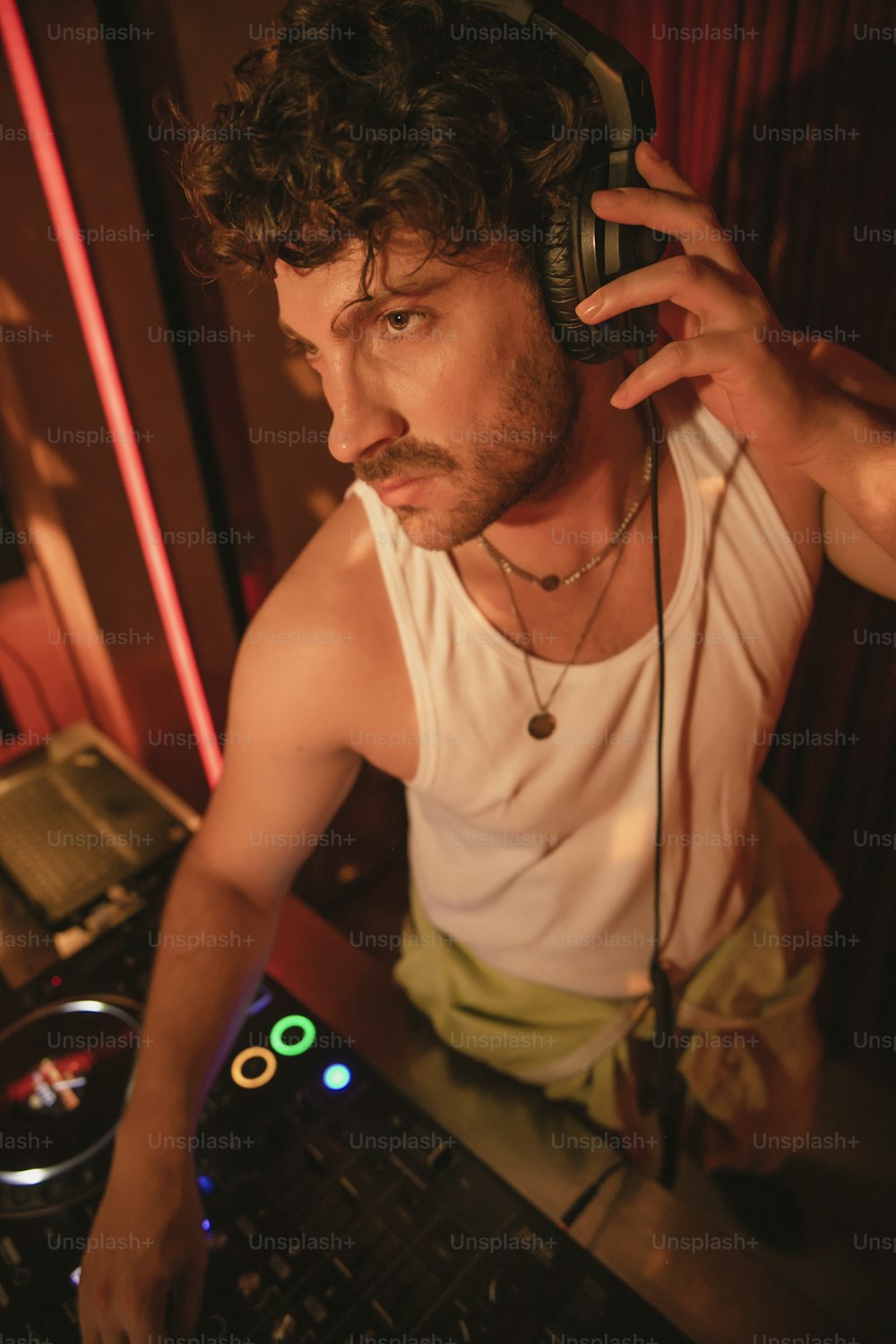 a man with headphones on sitting in front of a dj mixer