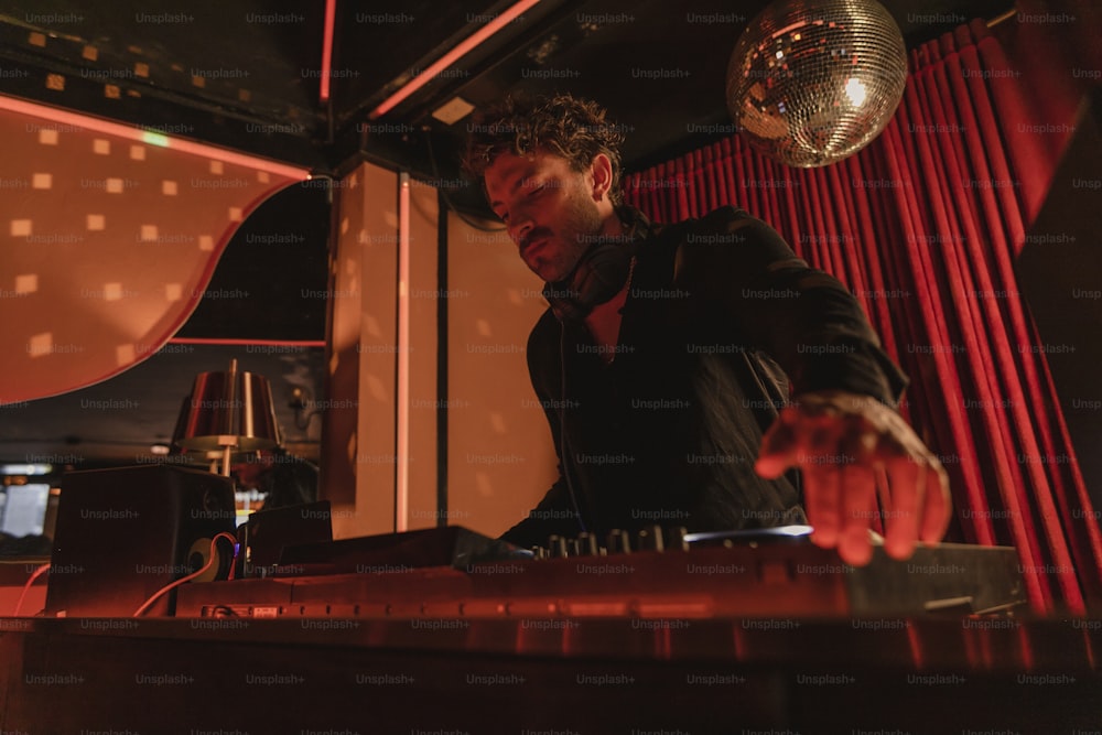 a man standing at a piano in front of a disco ball