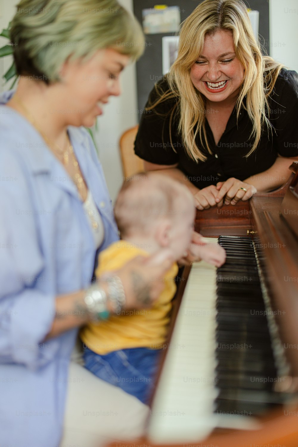 a woman and a baby are playing the piano