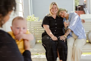 two women and a baby sitting on a bench