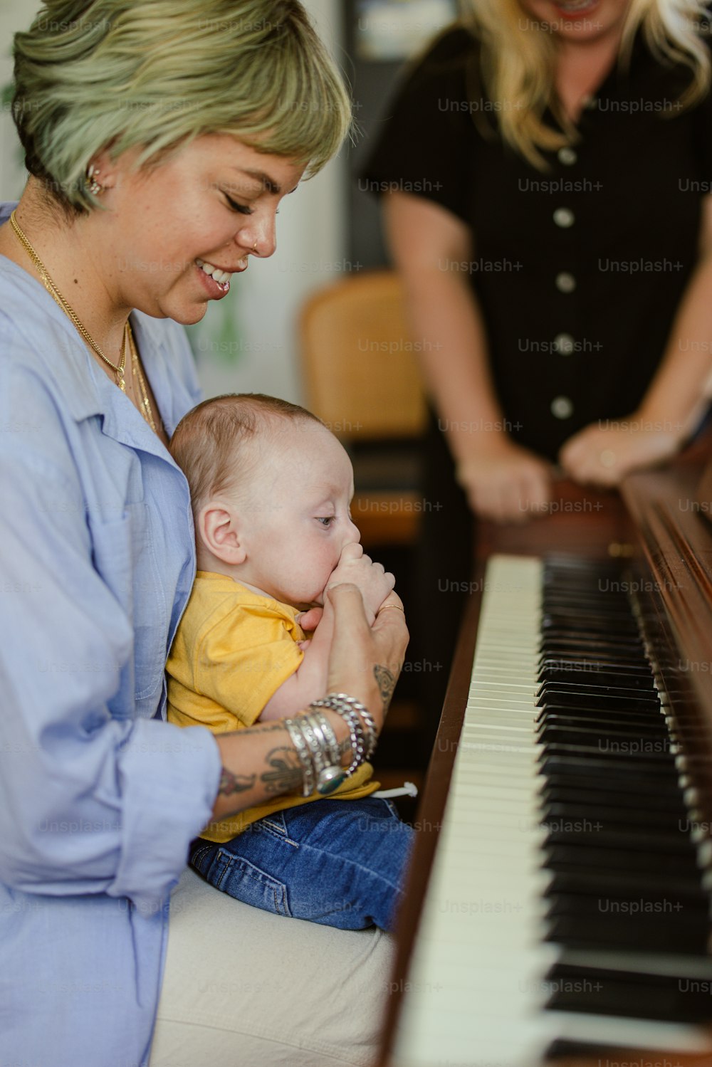 a woman sitting at a piano with a baby