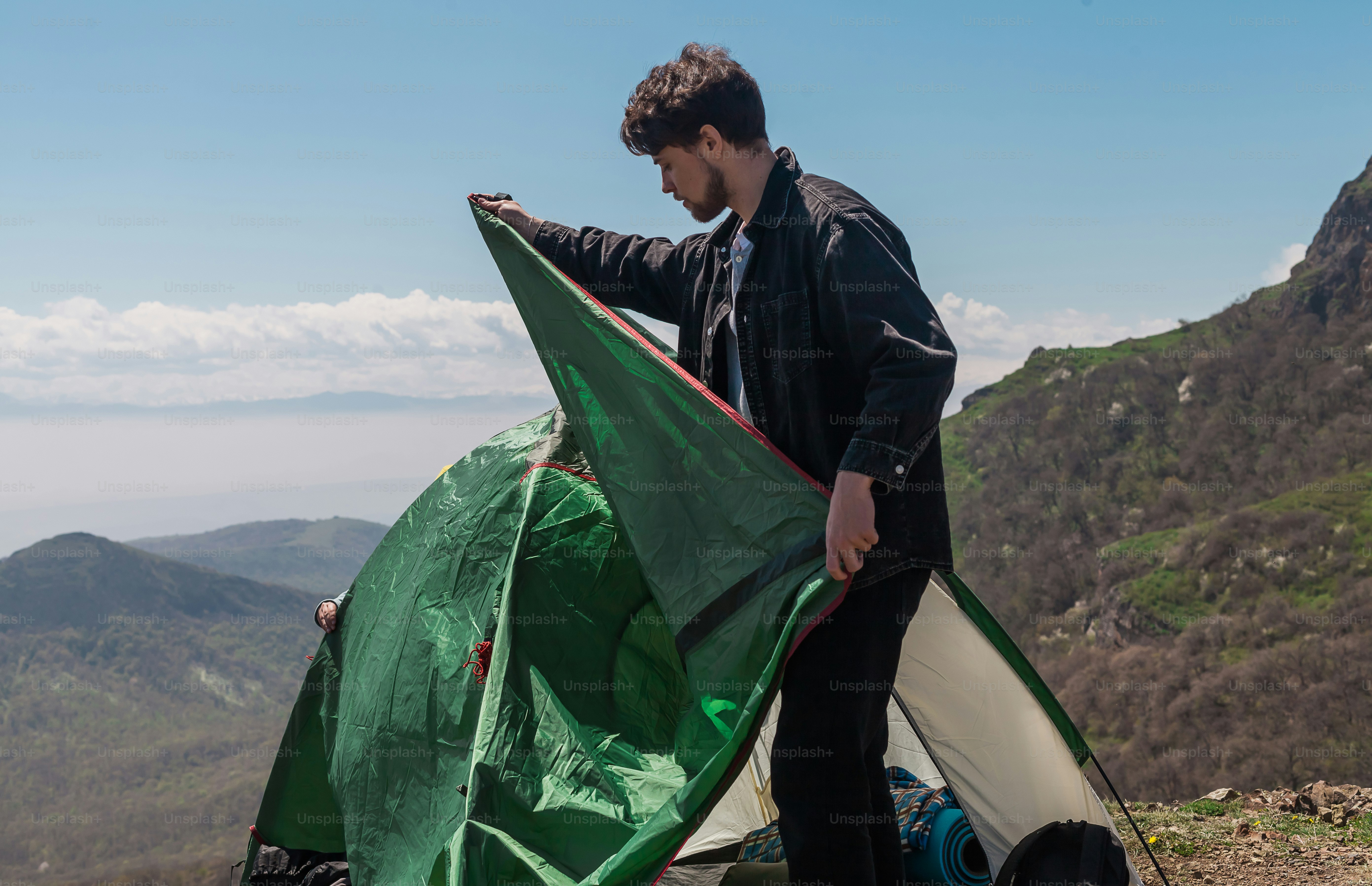 a man holding a green and white kite on top of a mountain