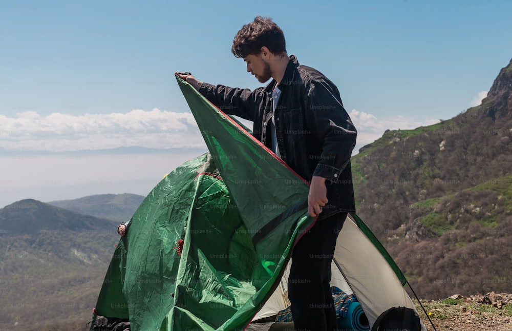 a man holding a green and white kite on top of a mountain