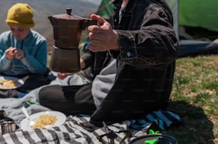 a person sitting on the ground with a coffee pot
