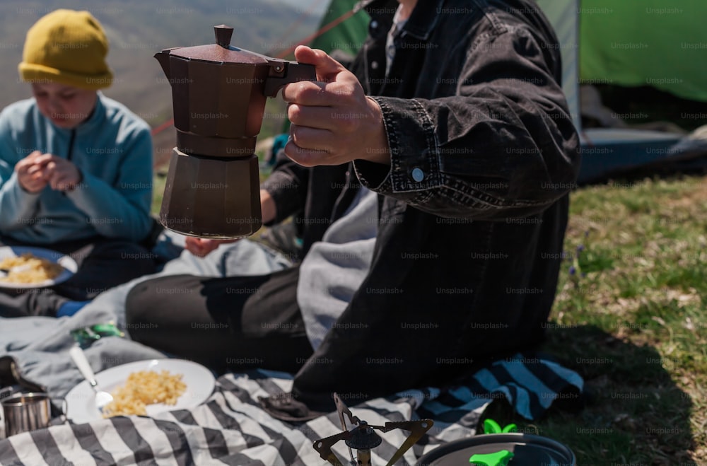 a person sitting on the ground with a coffee pot