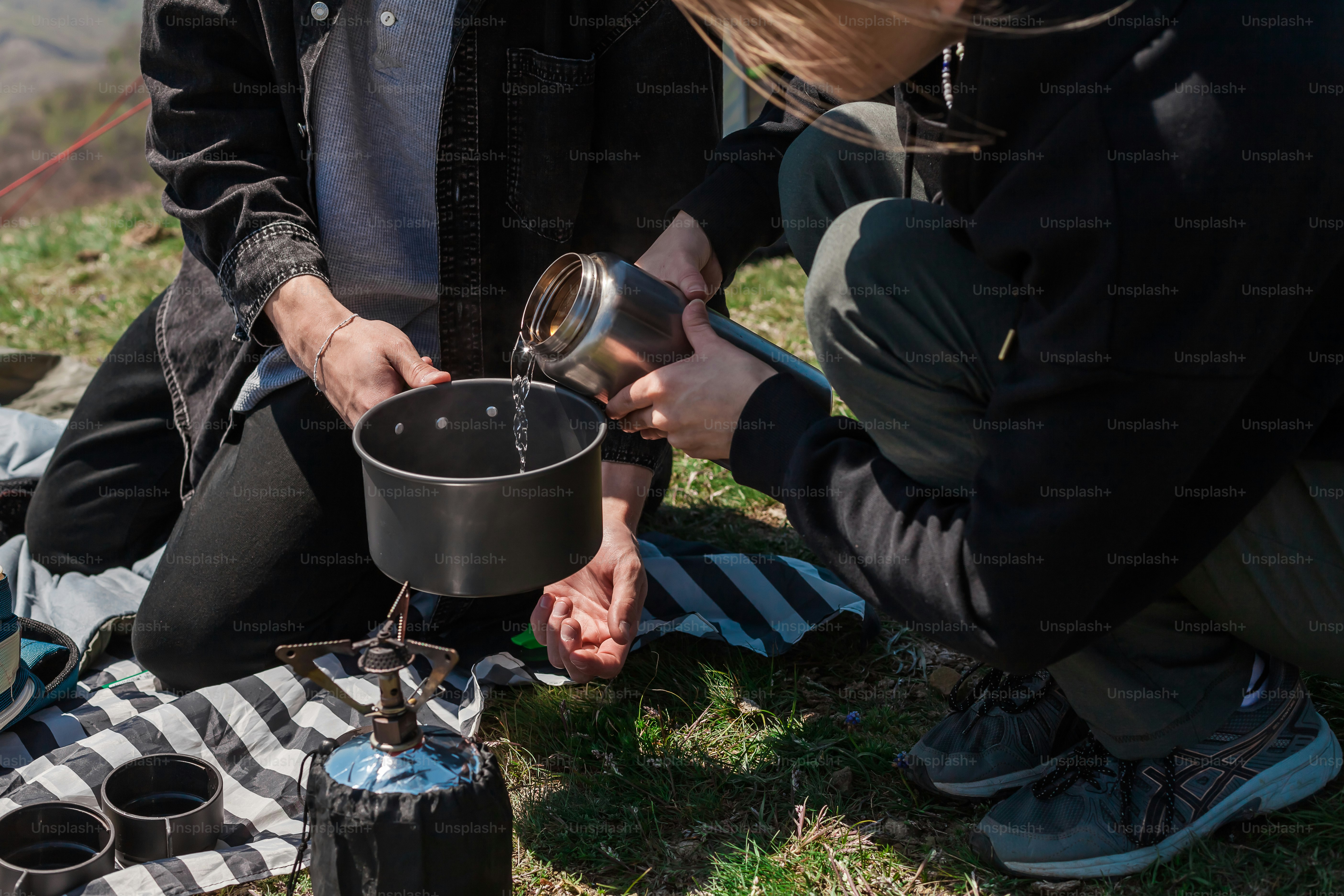a couple of people sitting on a grass covered field