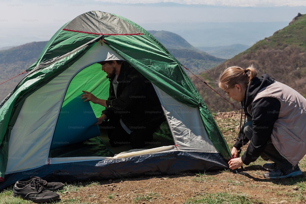 two women setting up a tent on top of a mountain