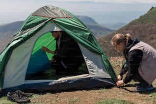 two women setting up a tent on top of a mountain