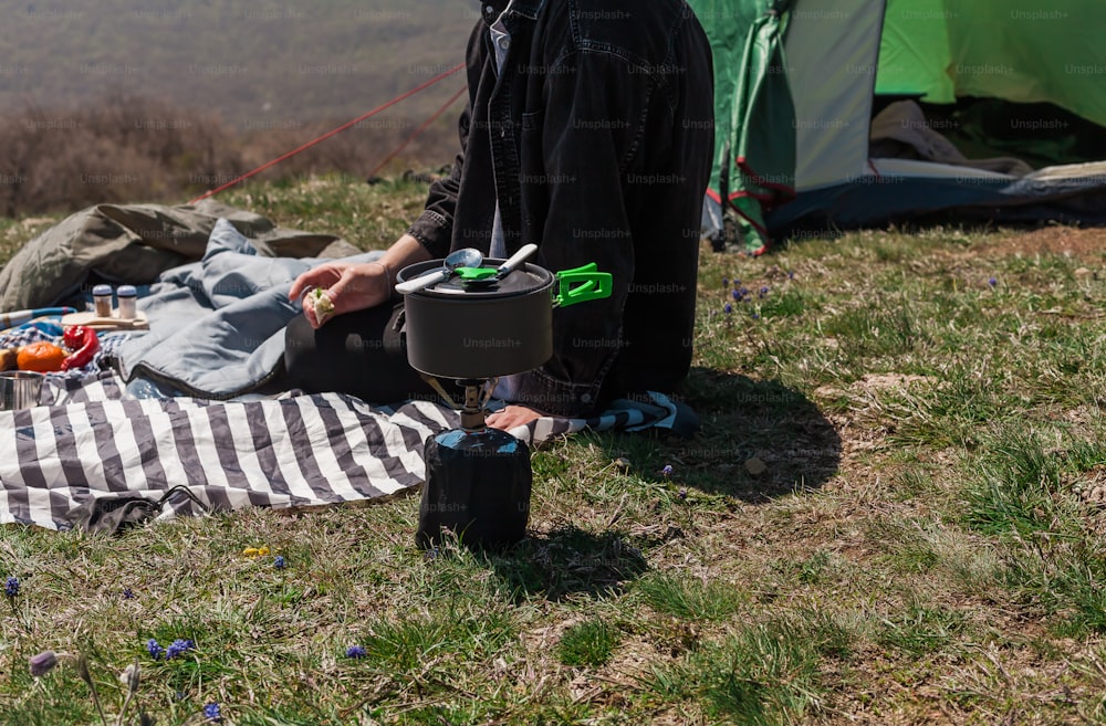 a man sitting on a blanket in front of a tent